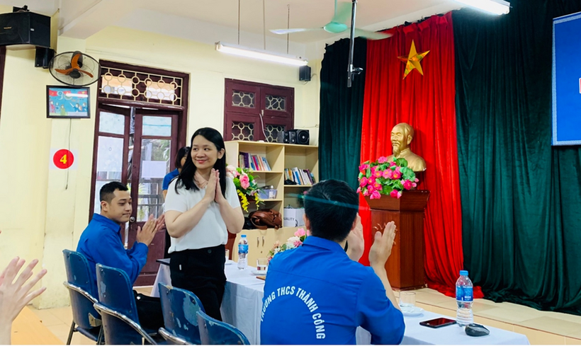 A person standing in front of a group of people sitting at a table

Description automatically generated with low confidence