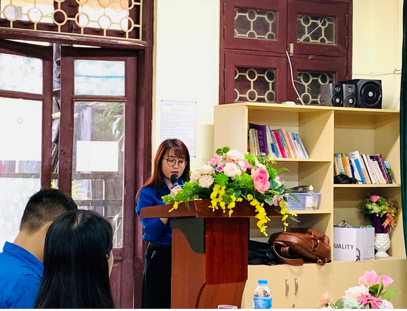 A person standing at a podium with flowers in front of a podium

Description automatically generated with low confidence