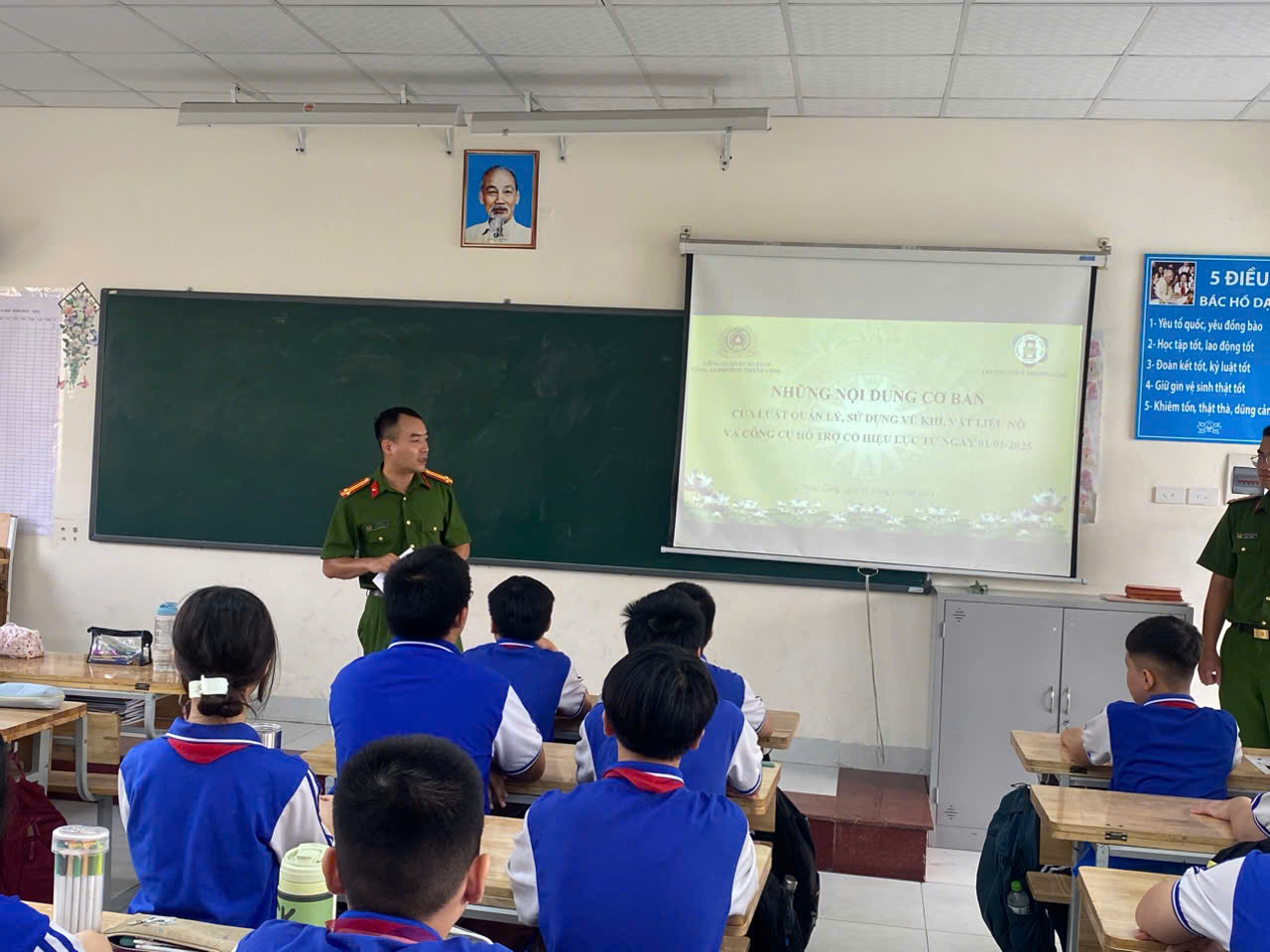 A person in uniform standing in front of a classroom

Description automatically generated