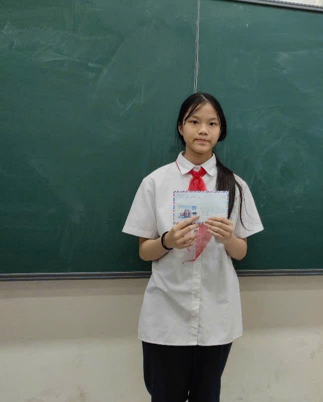 A child in a white shirt holding a piece of paper in front of a chalkboard

AI-generated content may be incorrect.
