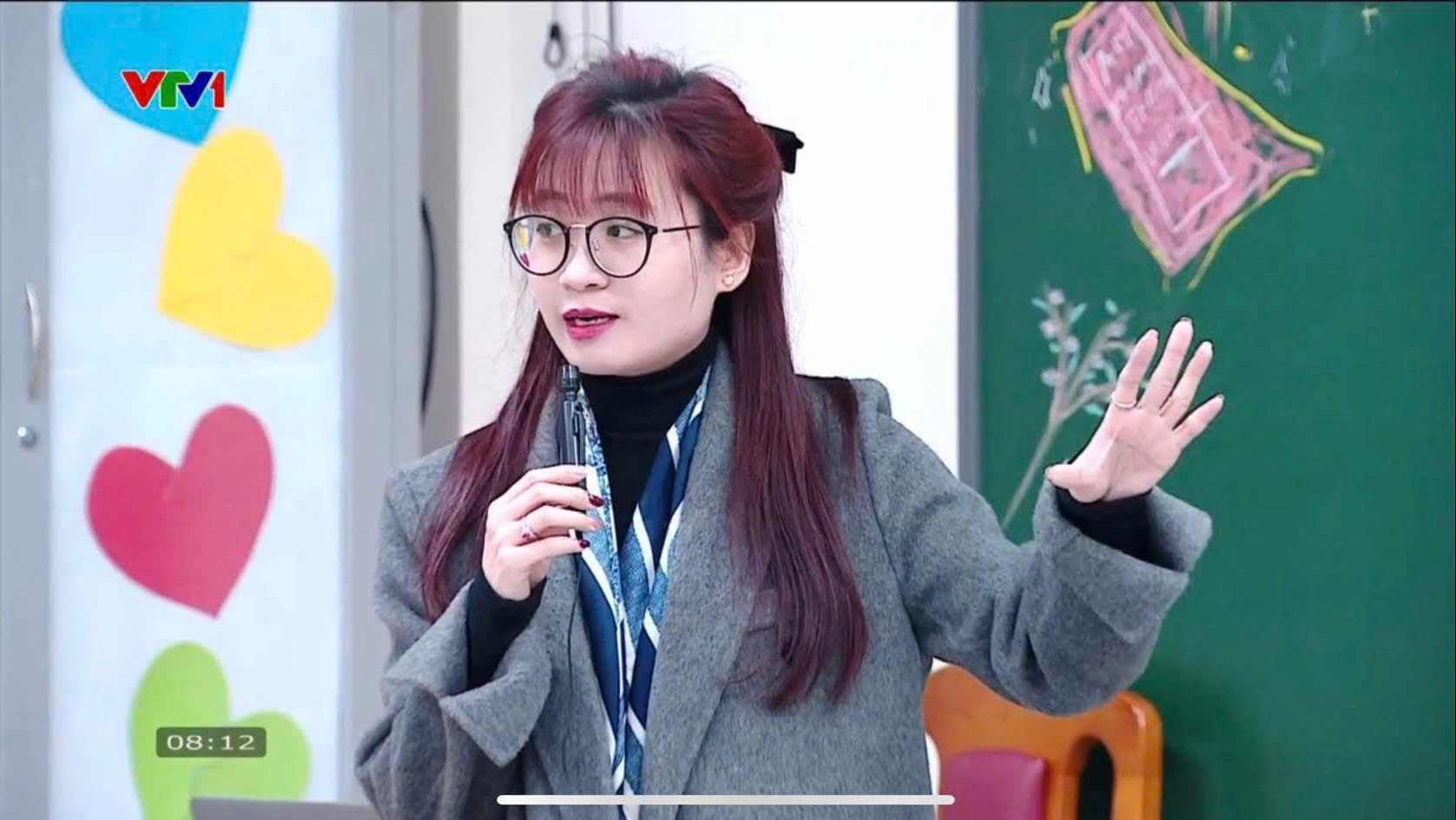 A person in glasses holding a pen
Description automatically generated