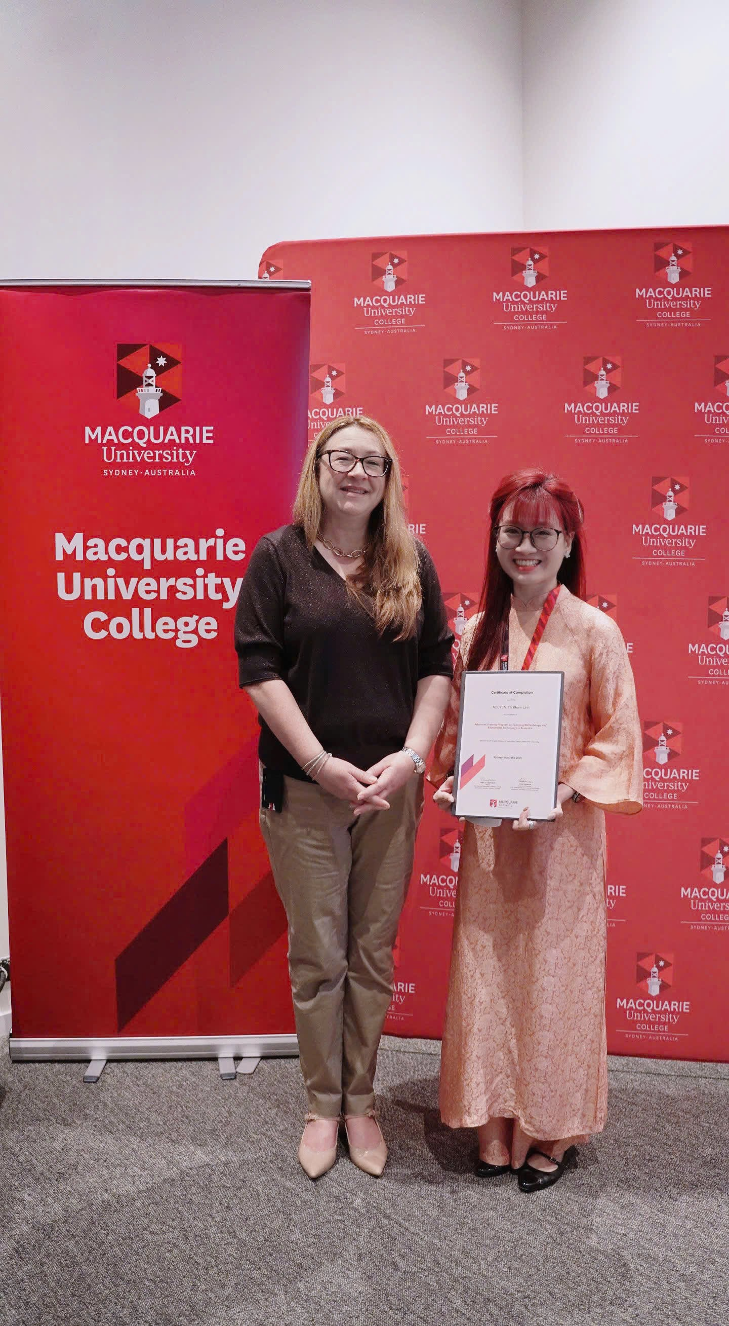 A couple of women standing in front of a red banner
Description automatically generated