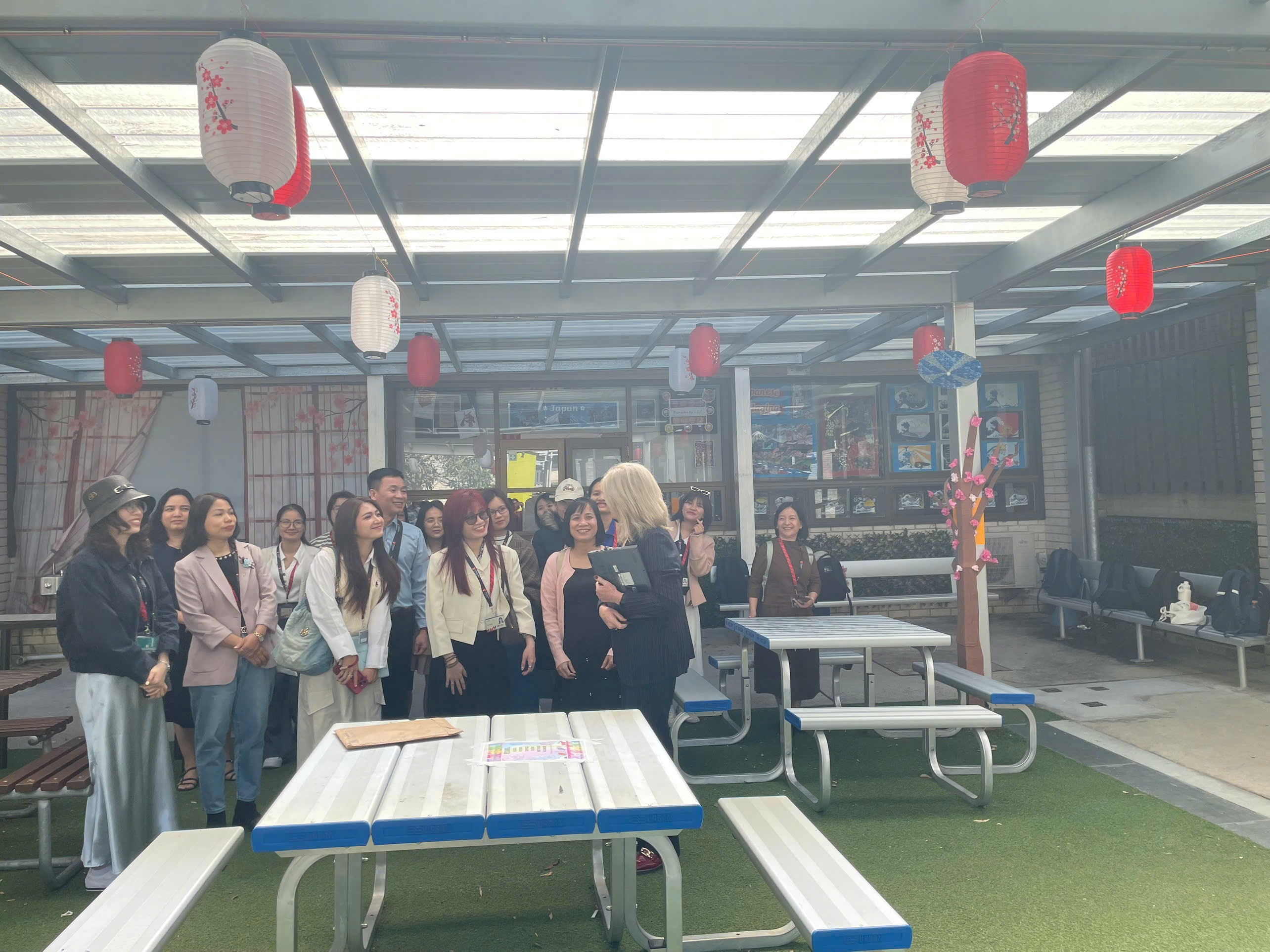 A group of people standing in a room with tables and red lanterns
Description automatically generated