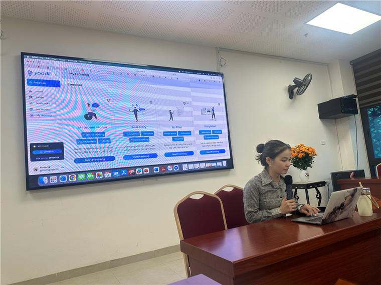 A person sitting at a desk with a microphone and a computer

Description automatically generated