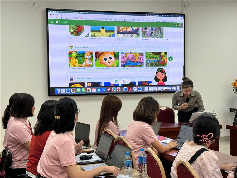 A group of people sitting at a table in front of a large screen

Description automatically generated