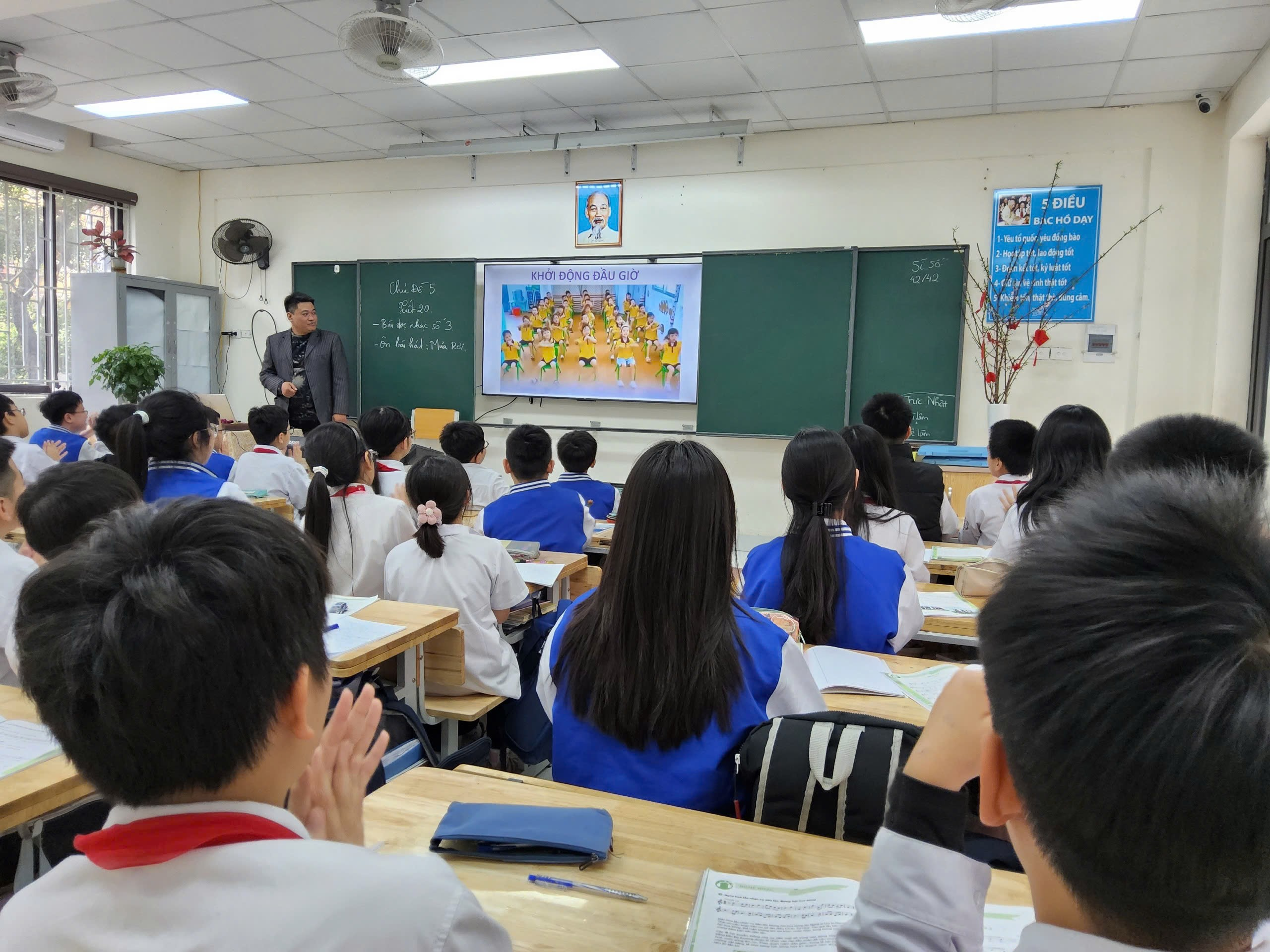 A person standing in front of a classroom with a group of students

Description automatically generated