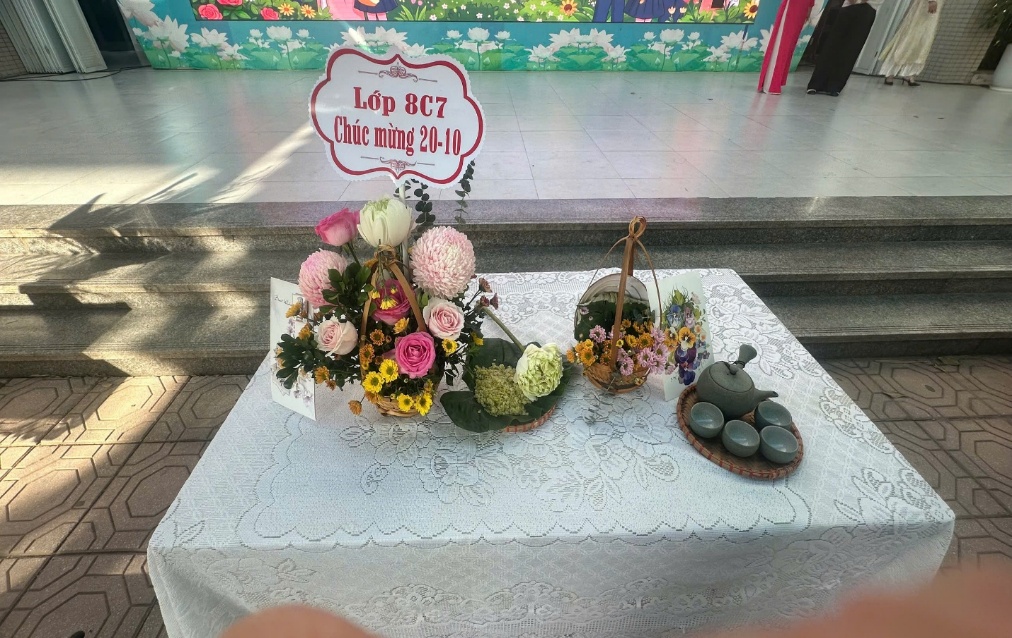 A table with flowers and a sign on it

Description automatically generated