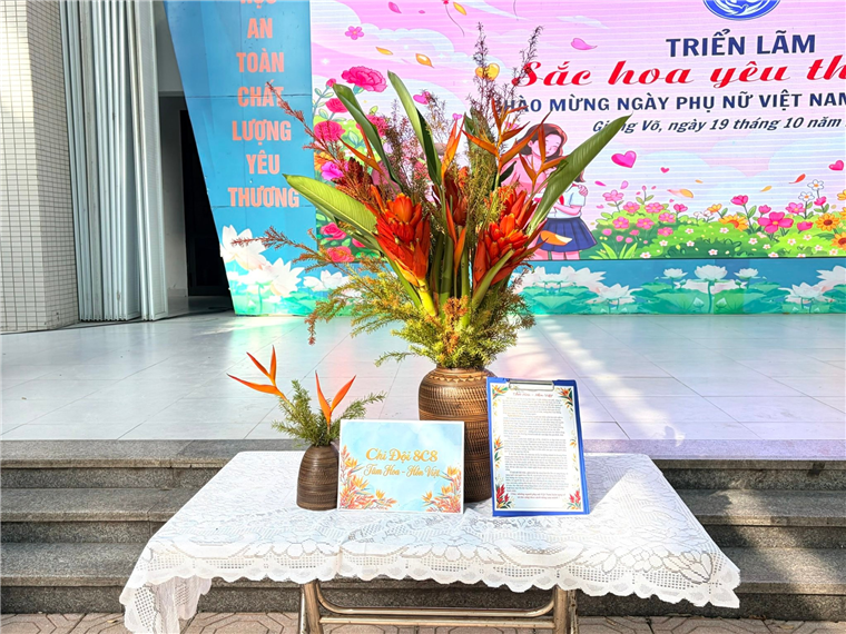 A table with flowers and a sign on it

Description automatically generated