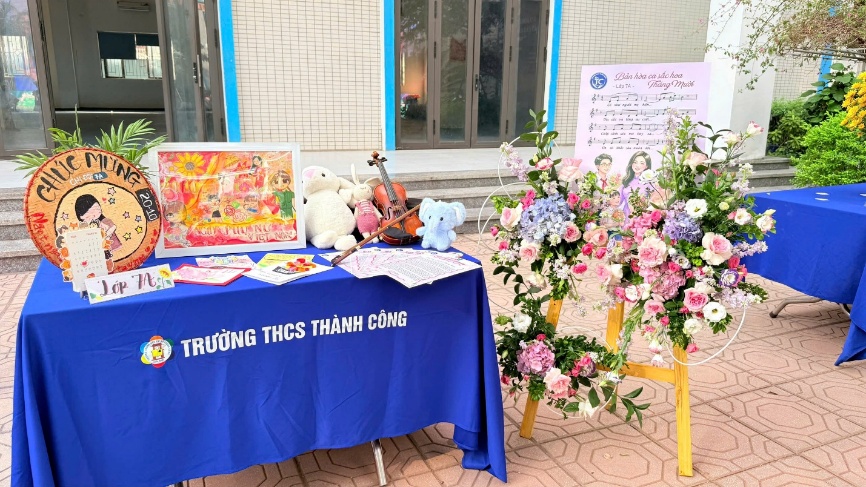 A table with flowers and a sign
Description automatically generated