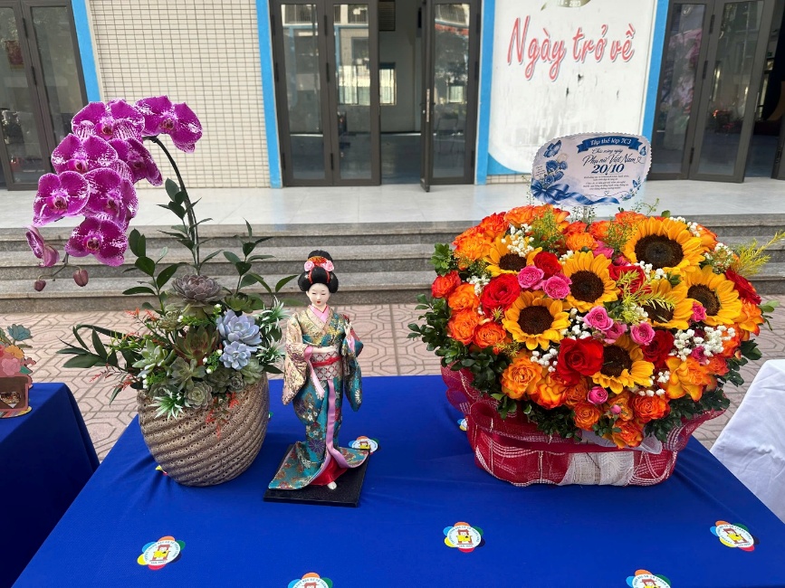 A table with a blue tablecloth and a statue of a person and a vase of flowers
Description automatically generated